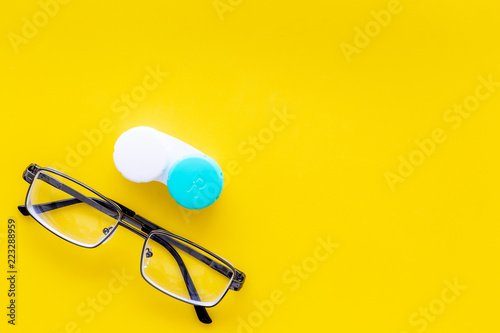 Products help see better. Glasses with transparent optical lenses and eye lenses on yellow background top view space for text closeup