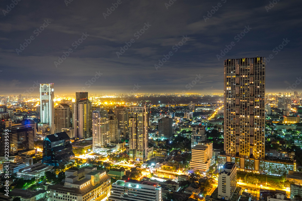 Naklejka premium Aerial Bangkok Skyline Buildings around Silom Area with Iconic Condominium in the Cloudy day with light from the City.
