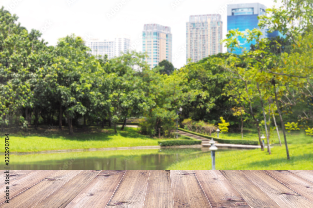 Wood table top over blurry green park in the city background.