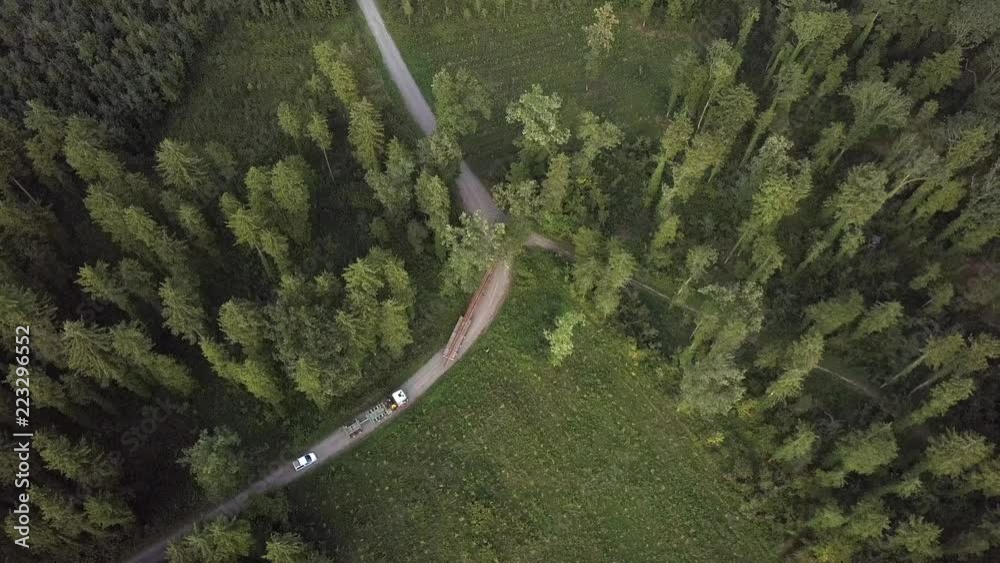Aerial footage of wood being transported with a logging truck, in a forest in Feldkirch, Voralberg, Austria. Double length log truck transporting trees to the sawmill.