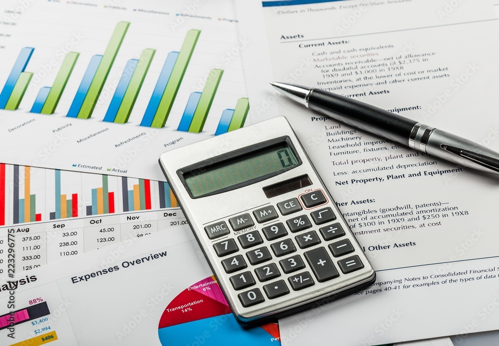 Pen and Calculator on Business Graphs and Charts Pen and Calculator on Business Graphs and Charts