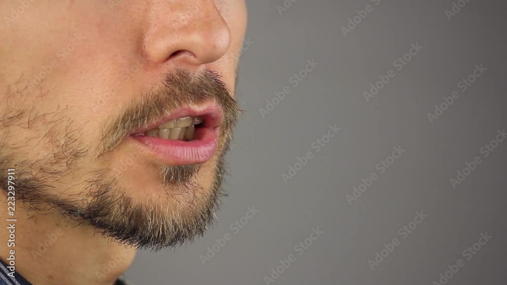 man speaks, closeup male mouth with a beard and mustache, gray background, side view, copy space man speaks, closeup male mouth with a beard and mustache, gray background, side view, copy space