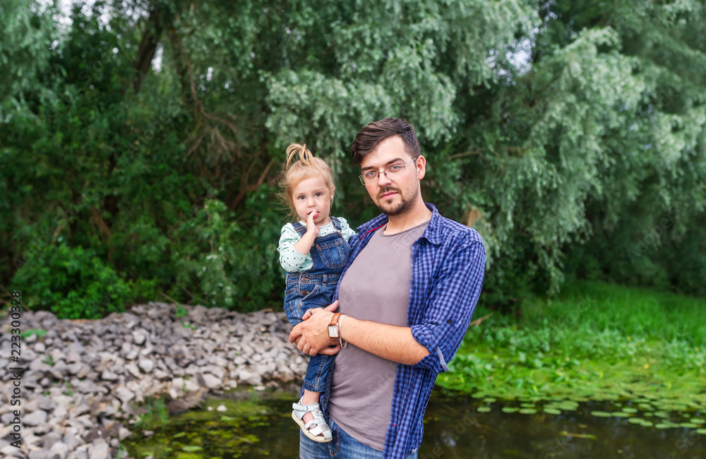 Father holds the little girl against the background of beautiful pond Father holds the little girl against the background of beautiful pond