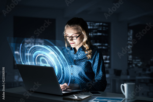 Obraz na płótnie Beautiful blonde in dark office working on laptop and getting ne w salonie