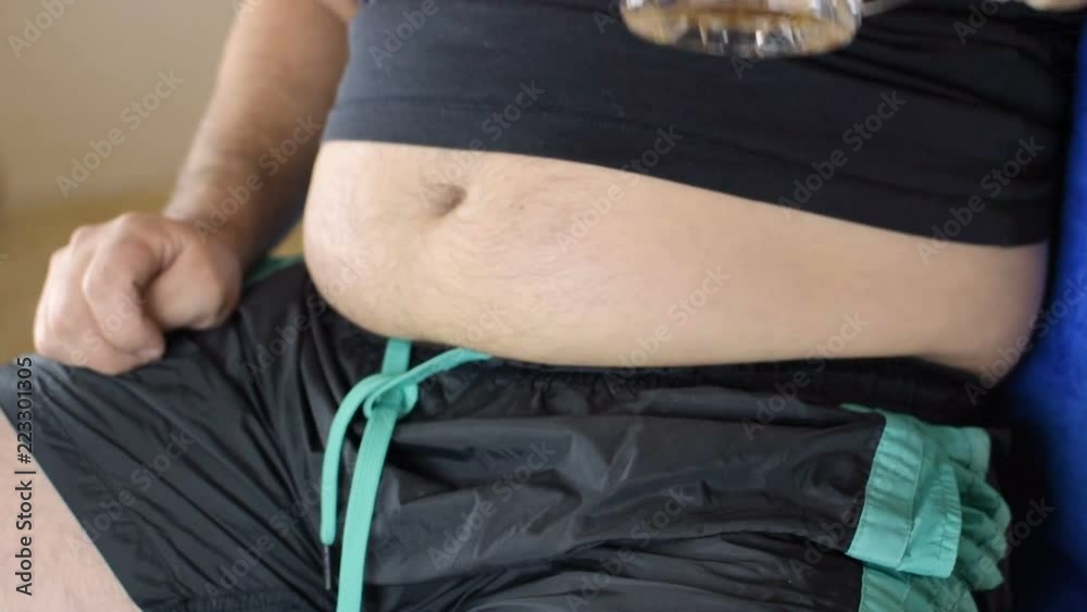 The fat man drinks beer. Beer belly from harmful food. Bad food, gluttony. Stockvideo Adobe Stock