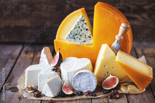 many different kinds of cheese with figs and nuts on an old wooden table in rustic style photo