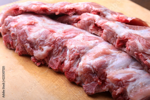 Raw Ribs on a rustic cutting board with salt, pepper and grinder for spices . copy space. Top View.