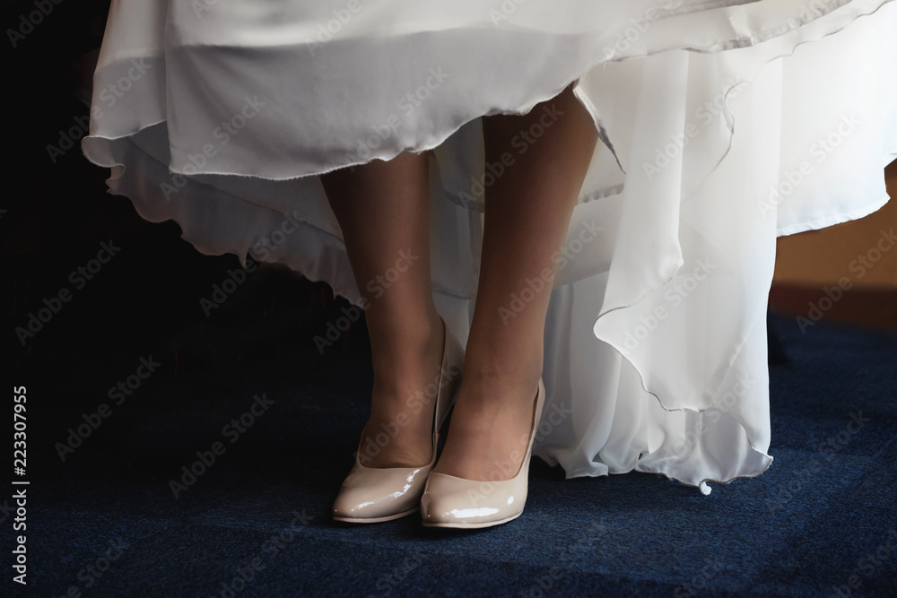 Girl's bridal gown and legs with shoes. Close view.