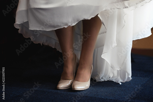 Girl's bridal gown and legs with shoes. Close view.