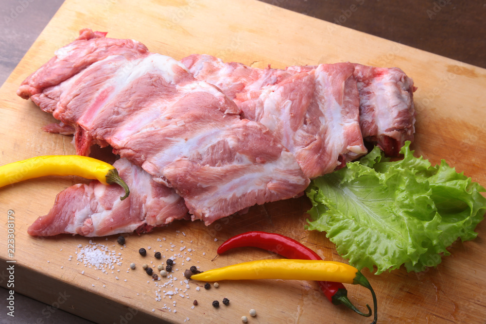 Raw Ribs on a rustic cutting board with salt, pepper and grinder for spices . copy space. Top View.