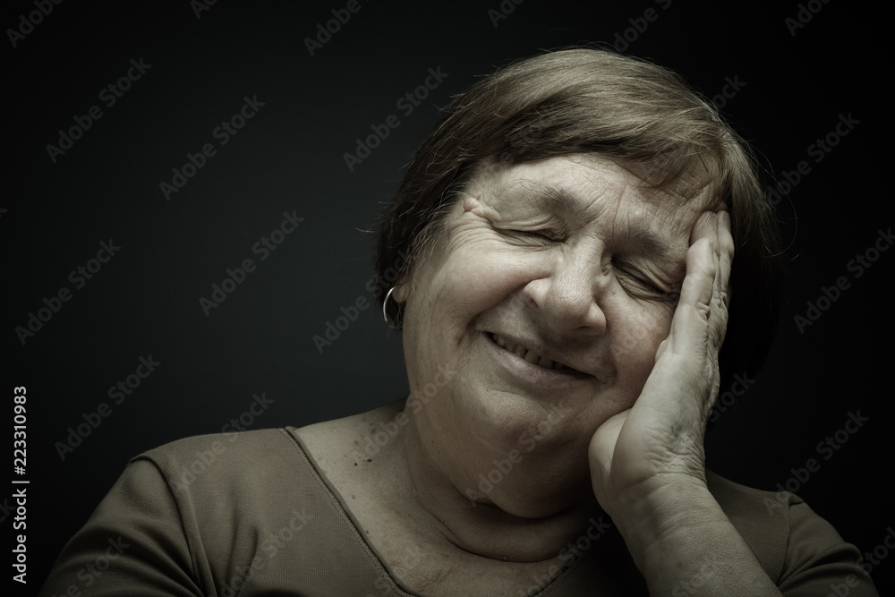 Studio portrait of elderly woman with hands near the face. Smile. Toned