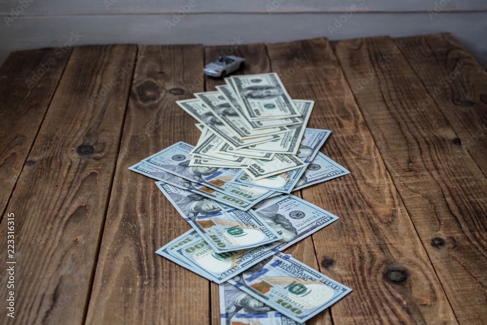 a stack of one hundred dollar bills on wooden background