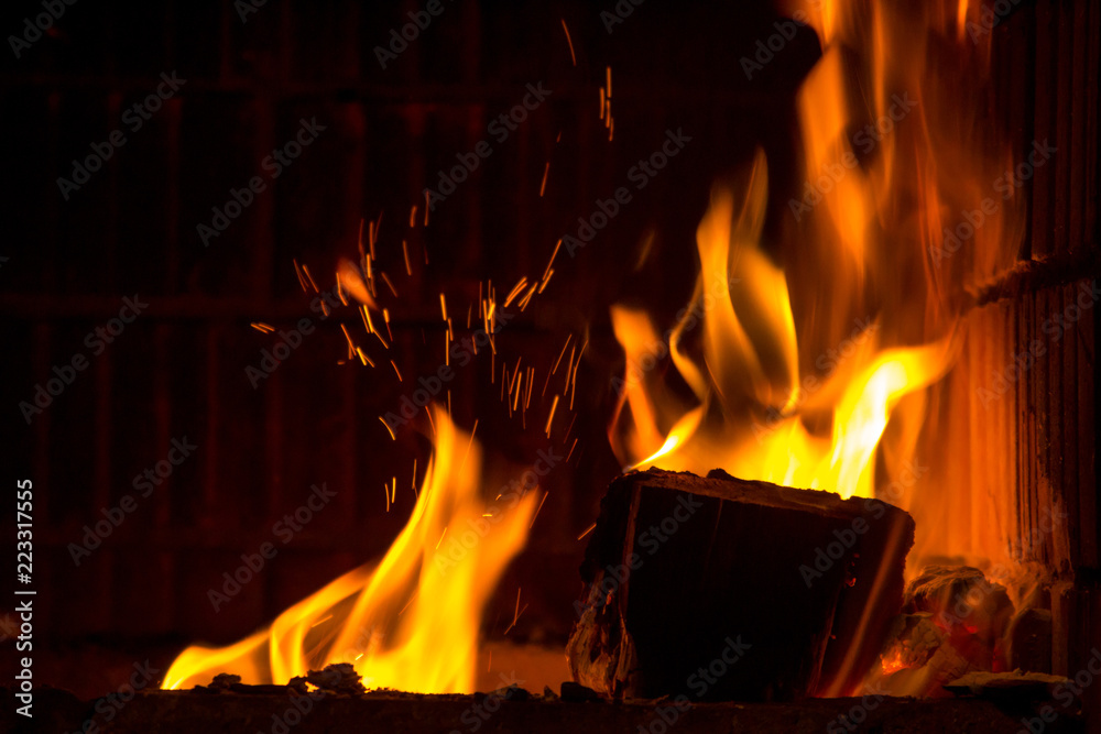 Obraz premium Burning firewood with flame tongues and spark in the fireplace