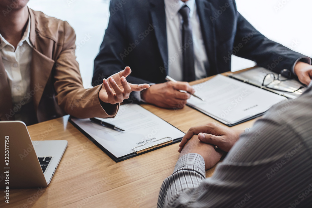 Two senior manager reading a resume during a job interview, Employer interviewing to ask young male job seeker for recruitment talking in office