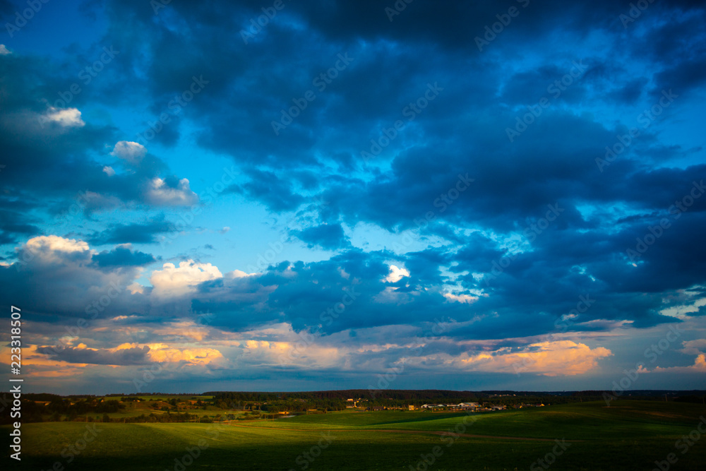 Dark blue clouds moving over green fields. Rural landscape