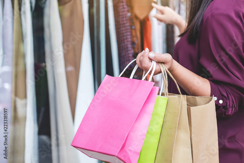 Consumerism, shopping lifestyle concept, Young woman holding colorful shopping bags and choosing fashion dress enjoying in shopping