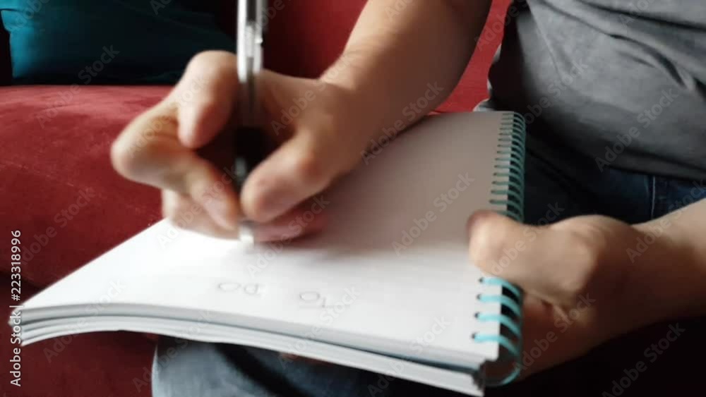 Male with a partially amputated index finger on his right hand sat down holding a pen and pad  writing a to do list.