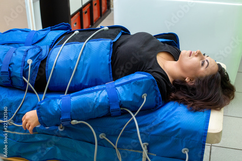 Photos Woman having procedure of anti cellulite massage on pressotherapy machine
