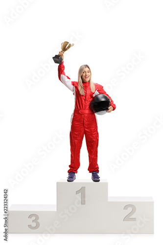Female racer on a winner's pedestal with gold trophy cup