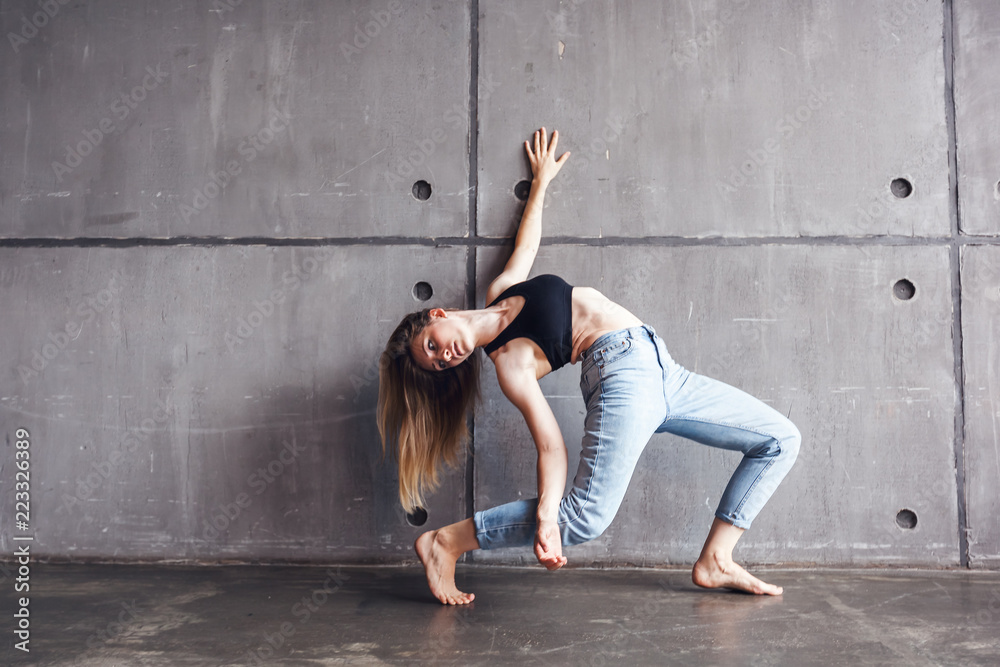 young beautiful woman in top and jeans dancing modern contemporary dance in the studio, contemporary art, harmony of body and soul, professional dancer