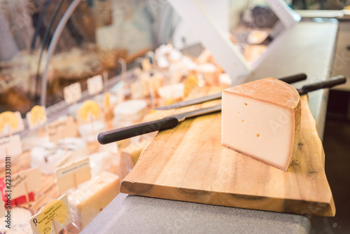 Cheese on a board at counter in delicatessen shop or deli