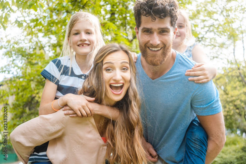 Family of four having fun, daddy and mommy are carrying the kids piggyback Family of four having fun, daddy and mommy are carrying the kids piggyback