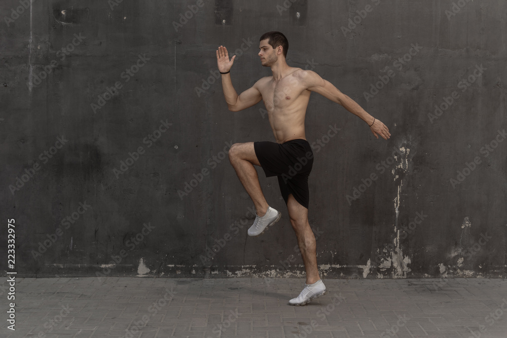 Young athlete man, naked torso, running against a gray wall Young athlete man, naked torso, running against a gray wall