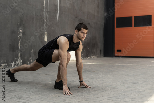 Sportsman starting his sprint on a gray industrial wall backgrou