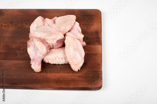 Raw chicken wings on cutting board on white background.