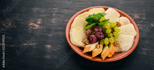 Cheese on a plate. Brynza and Suluguni cheese. On the old wooden background. Free space for text. Top view.