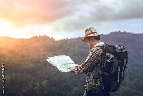 hiker with backpack standing holding map looking for checking on the mountain