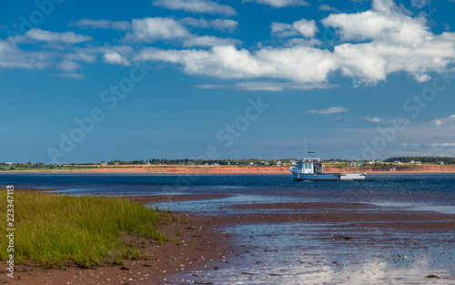 Lobster fishing boat sailing past sandy beaches in rural Prince Edward Island, Canada.