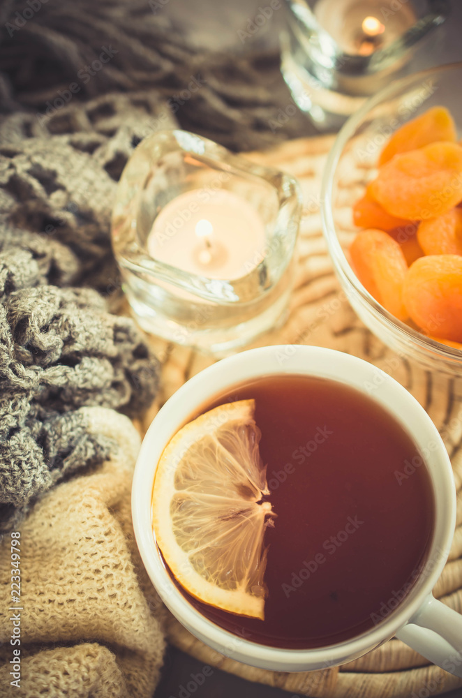 Cup of tea and dried apricots on a table, candles and knited blanket. Cup of tea and dried apricots on a table, candles and knited blanket.