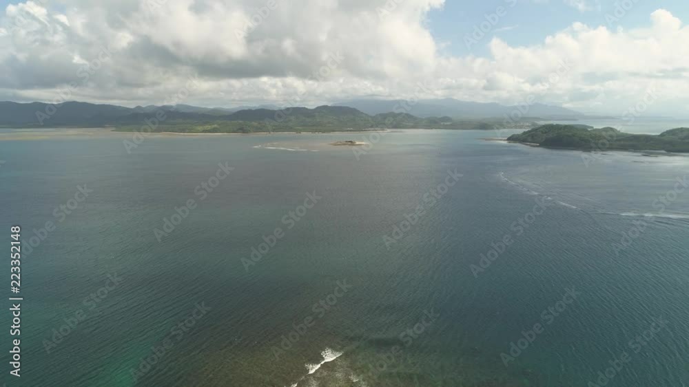 Aerial view of islands and coral reefs with turquoise water in blue lagoon, Philippines, Santa Ana. Seascape ocean coastline, mountains and blue sky with clouds. Tropical landscape in Asia. Aerial view of islands and coral reefs with turquoise water in blue lagoon, Philippines, Santa Ana. Seascape ocean coastline, mountains and blue sky with clouds. Tropical landscape in Asia.
