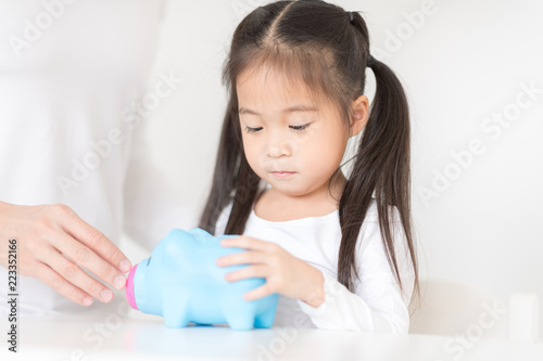 Little girl playing put a coin into piggy bank with father. Educational toy management future lifestyle.Education concept.