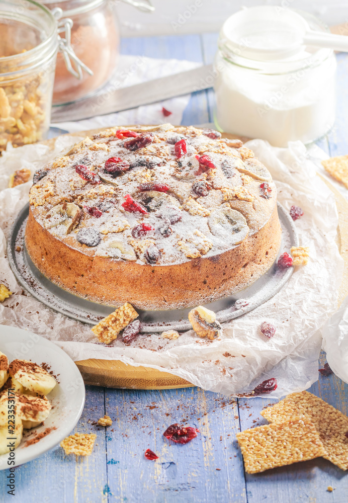 Banana cake with nuts, sesame and cranberry on a wooden table