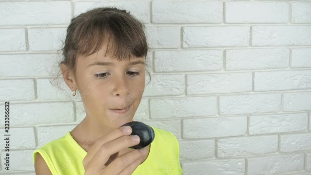 The child eats plum. A little girl throws a plum. The child eats plum. A little girl throws a plum.