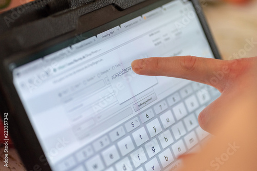 Closeup image of woman's hand holding black tablet and typing on screen