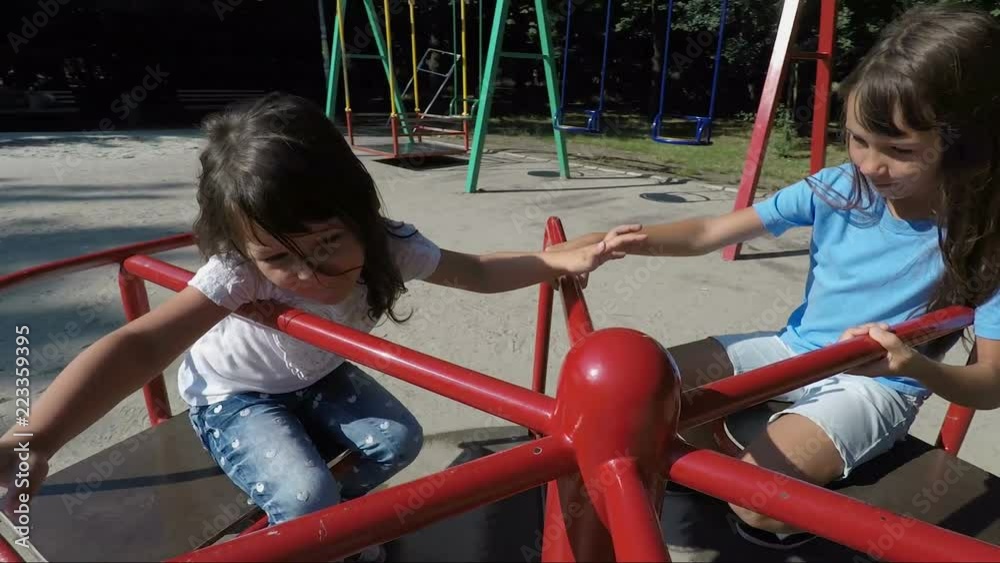 Children in the playground. Happy little girls are spinning on the carousel. Children in the playground. Happy little girls are spinning on the carousel.