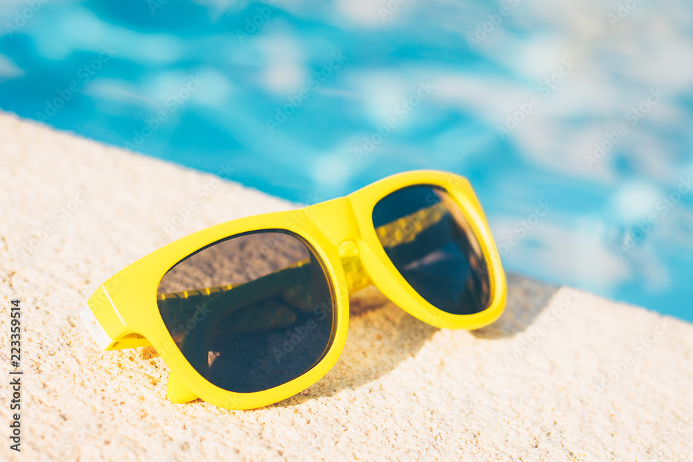 Yellow sunglasses on the stone side of the pool