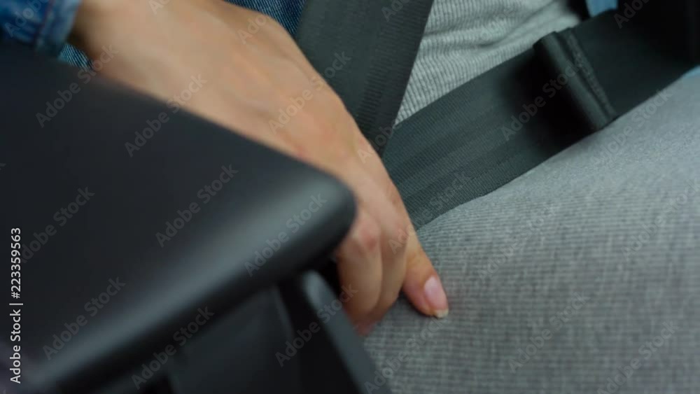 Female hand fastening car safety seat belt while sitting inside of vehicle before driving Female hand fastening car safety seat belt while sitting inside of vehicle before driving