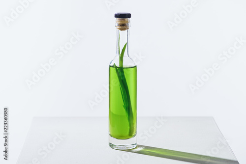 bottle of natural herbal essential green oil with aloe vera on white cube