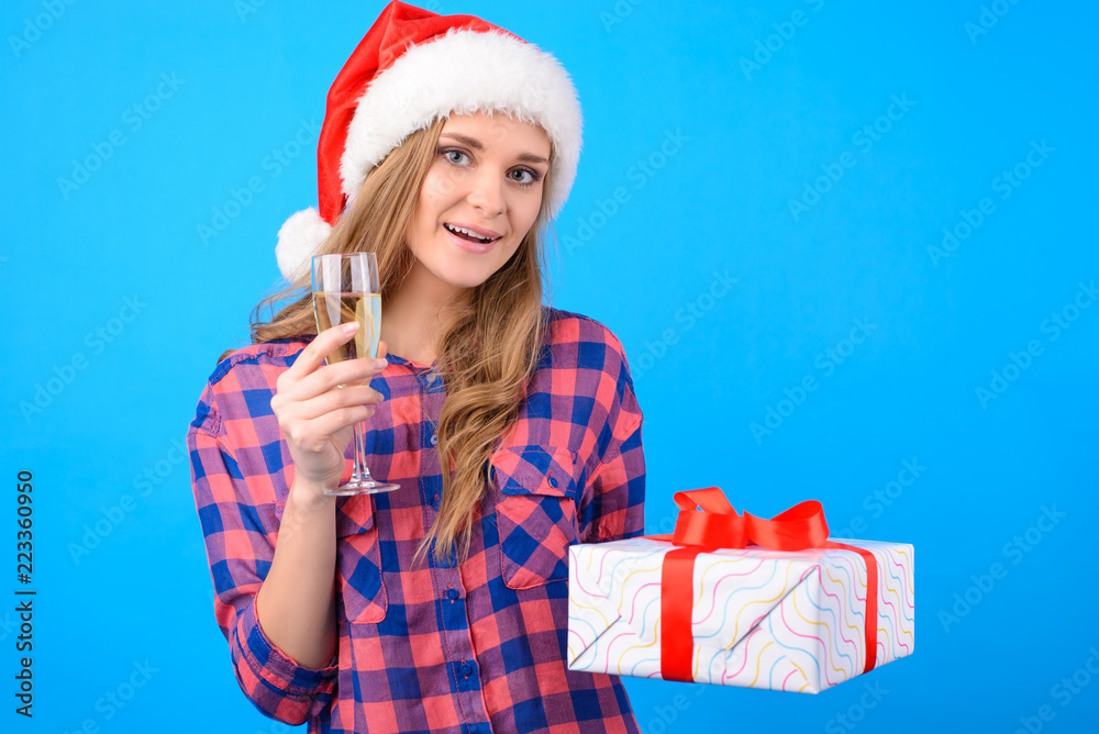 Obraz premium Concept of having New Year corporate event at work. Beautiful happy woman saying toast and holding a glass of bubbly Champagne and holding a giftbox