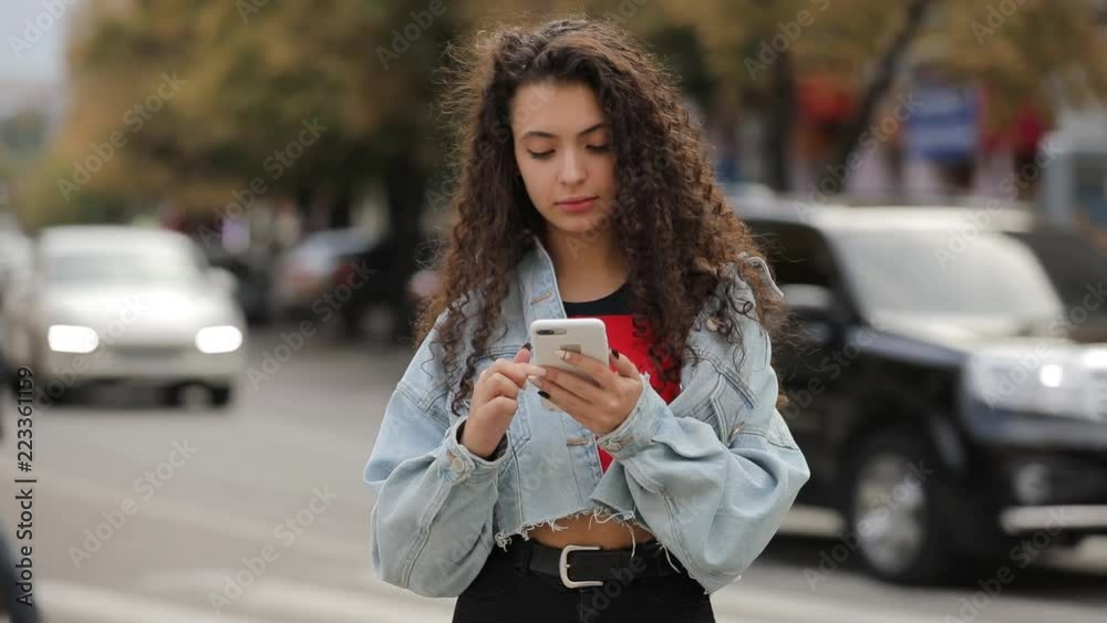 Teen girl using smartphone texting browsing messages a mobile phone, communicate in city Teen girl using smartphone texting browsing messages a mobile phone, communicate in city