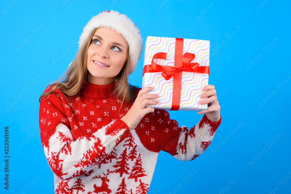 What can be there? Close up portrait of excited joyful happy woman with a present box, isolated on blue background What can be there? Close up portrait of excited joyful happy woman with a present box, isolated on blue background