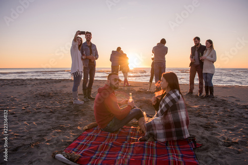 Couple enjoying with friends at sunset on the beach photo