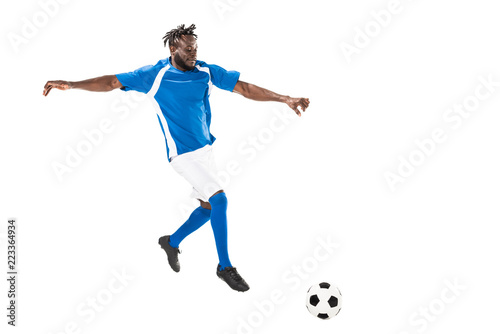 Fototapeta Naklejka Na Ścianę i Meble -  full length view of athletic african american soccer player hitting ball isolated on white