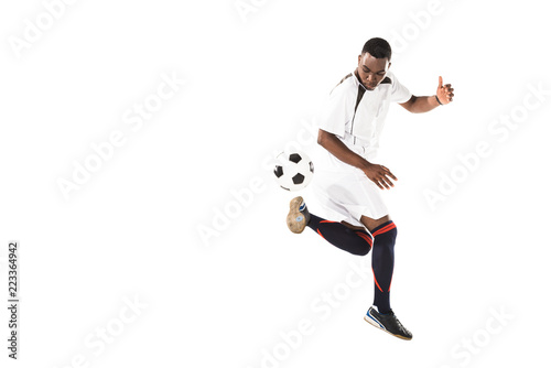 Fototapeta Naklejka Na Ścianę i Meble -  full length view of athletic african american soccer player kicking ball isolated on white