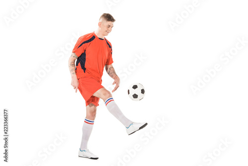 full length view of smiling young sportsman kicking soccer ball isolated on white © LIGHTFIELD STUDIOS