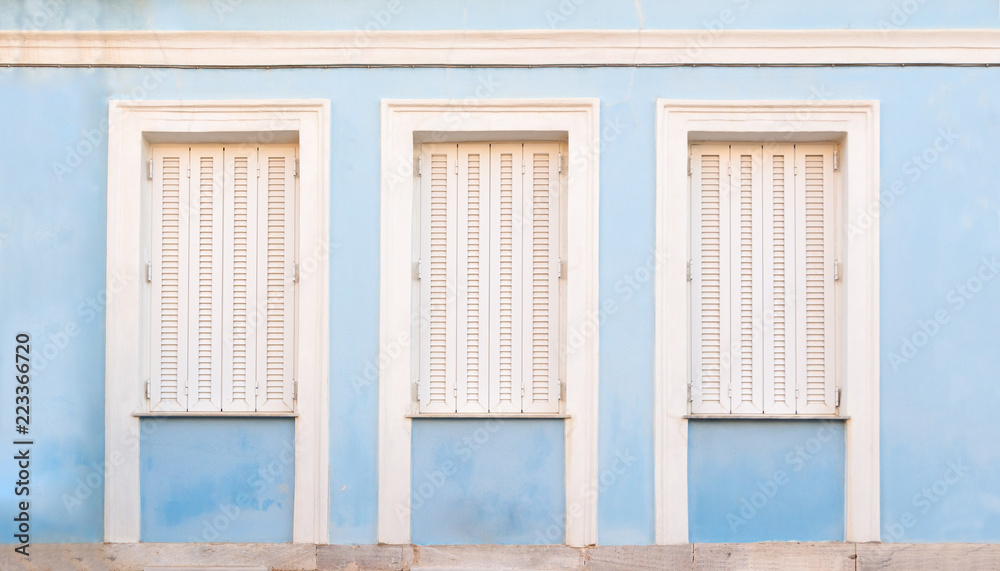 Fototapeta premium Wooden white retro style windows with shutters, on blue painted wall.